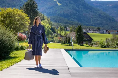 Junge Frau im Bademantel unterwegs zum Pool