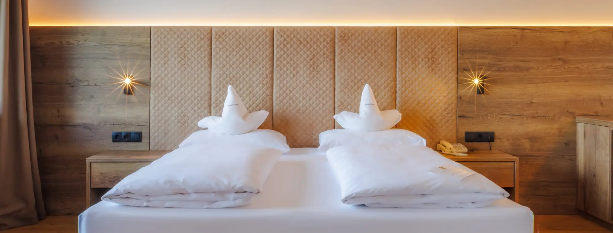 Ein großes Doppelbett mit weißer Bettwäsche und beigen Kopfteil
