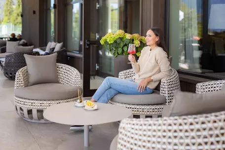 Junge Frau entspannt bei einem Drink auf der Terrasse des Hotel Royal Hinterhuber